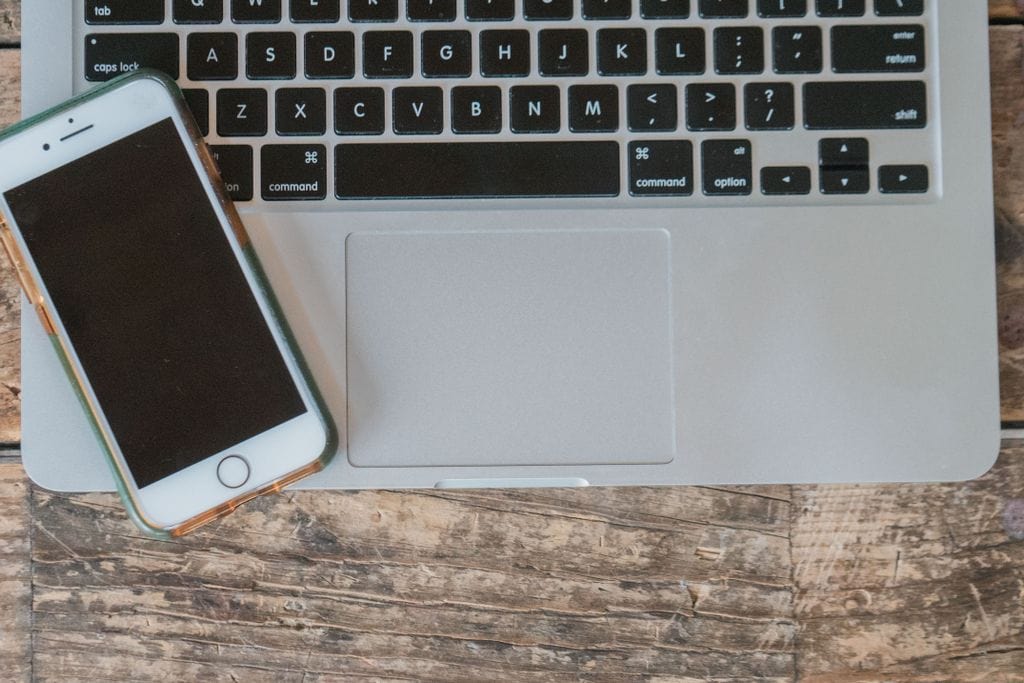 Contact Cecil Helton - Overhead view of a laptop and smartphone placed on a rustic wooden desk. Ideal for tech-themed projects.